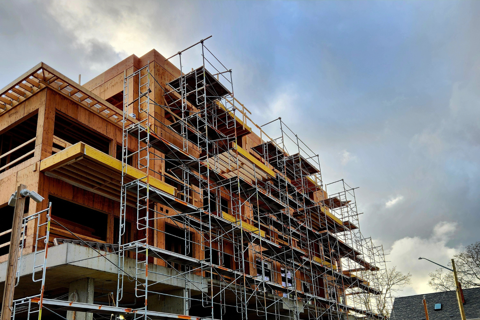 Multi-unit residential building under construction with wood framing and scaffolding in Greater Vancouver